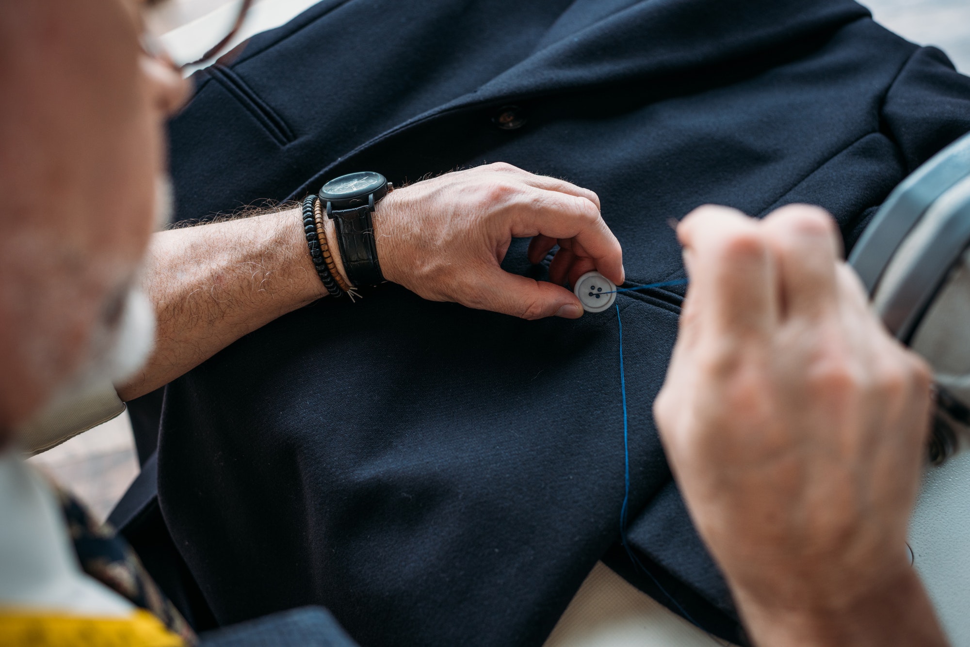 cropped-image-of-tailor-sewing-button-to-jacket-at-sewing-workshop.jpg